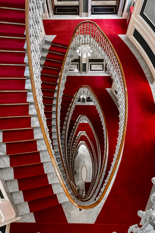 Dramatic staircase inside Hotel Bristol Palace in Genoa, Italy, with sweeping architectural lines and historic interior detail.