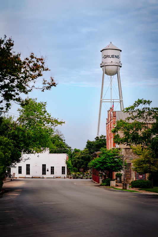 Street scene in Gruene, Texas, featuring the iconic Gruene water tower, historic buildings, and a quiet road in New Braunfels.