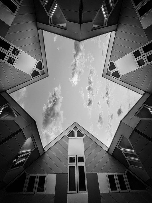 Upward view of Rotterdam cube houses forming geometric angles around the sky in a bold architectural composition in black & white.